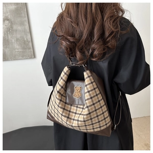 Détail du sac à dos à carreaux avec broderie ours et base en cuir porté par un modèle