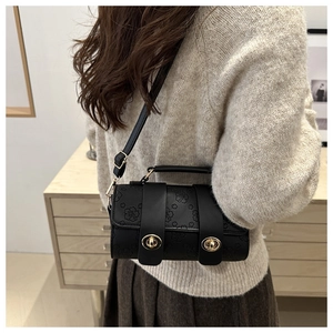 Detail of black embossed floral Boston bag with gold turn-locks worn by a model