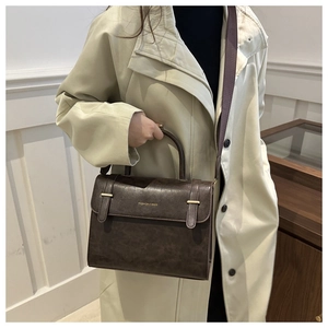 Détail d'un sac messager vintage marron foncé avec poignée et bandoulière large en tissu