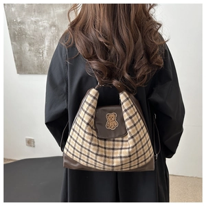 Détail du sac cabas en laine à carreaux avec cuir marron et écusson ours porté au dos