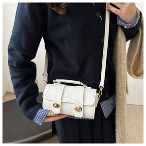 Detail of white cylinder bag with 3D floral embossing and gold metal twist locks