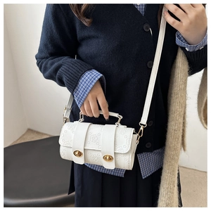 White floral embossed crossbody bag with golden hardware shown on a model