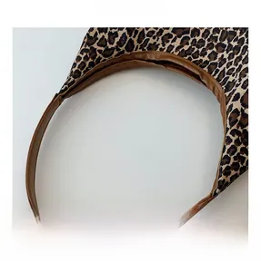 Detail shot of leopard print canvas bag featuring premium brown leather handles and stitching