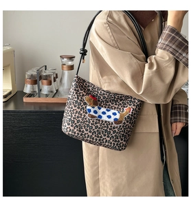 Detail of leopard print bucket bag featuring cartoon dachshund embroidery and knotted strap