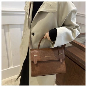 Sac bandoulière marron vintage en similicuir avec boucles et poignée porté par un mannequin