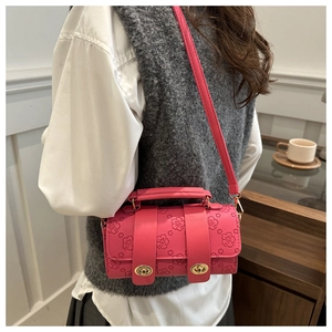 Detail of hot pink embossed leather cylinder bag with floral patterns and gold metal buckles