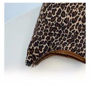 Detail view of leopard print fabric with premium brown leather piping and precise stitching