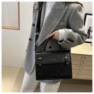 Détail du sac messager en cuir noir mat avec lettrage doré et large bandoulière réglable