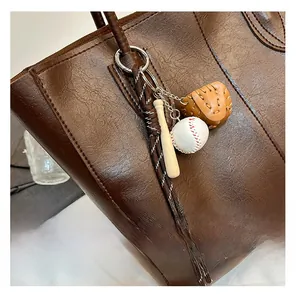 Detail of retro brown lychee tote bag with baseball bat and glove charm accessories