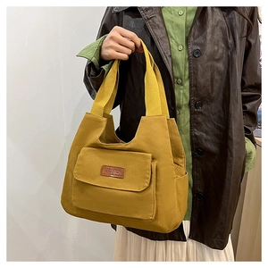 Detail of mustard yellow canvas tote bag featuring a brown PU fashion leather patch