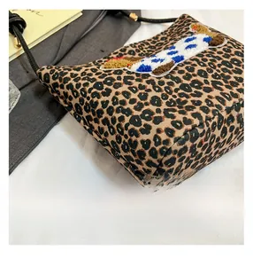 Détail du sac à main léopard avec écusson chiot en peluche et finitions de couture