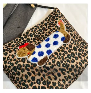 Détail du sac léopard avec écusson brodé en forme de teckel à pois bleus sur le devant