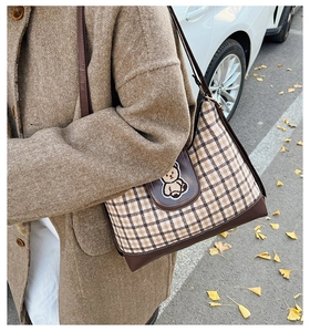 Close-up of vintage checkered tote bag with embroidered bear on an autumn street