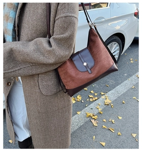 Détail du sac cabas vintage en daim marron avec empiècement cuir et bouton métallique