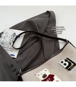 Close-up of cute bear embroidery on beige canvas tote bag with brown leather straps