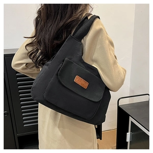 Sac fourre-tout en toile noire avec poche à rabat et étiquette mode sur un modèle