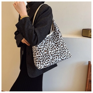 Detail of trendy leopard print tote bag with long white shoulder strap worn by model