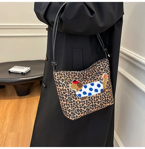 Détail du sac seau léopard avec écusson teckel porté sur un manteau noir élégant