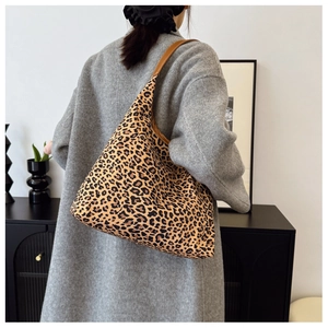 Fashionable leopard print tote bag with brown leather strap shown on a model