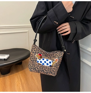 Detail of leopard print bucket bag featuring a cartoon dachshund embroidery and thin straps