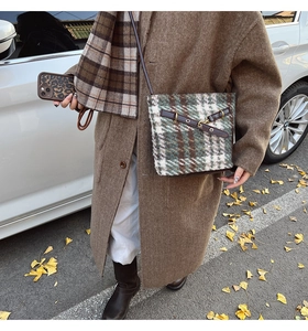 Détail du sac seau en laine à carreaux verts avec bordure en cuir et boucles métal