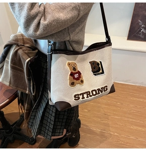 Detail of canvas shoulder bag with brown leather trim and cute embroidered bear patches