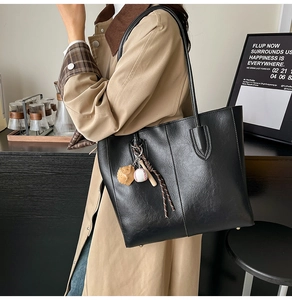 Detail of black tote bag with vintage baseball charms and protective metal feet on bottom
