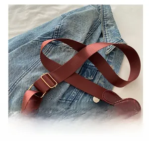 Detail of burgundy V-quilted crossbody bag with adjustable wide fabric shoulder strap