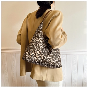 Detail view of large leopard print tote bag with brown shoulder straps and canvas texture
