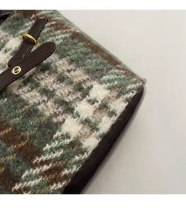 Détail du tissu en tweed à carreaux vert avec bandoulière en cuir et boucle