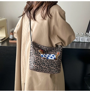 Detailed close-up of leopard print bucket bag with embroidered dachshund on trench coat