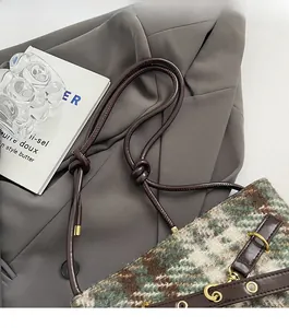 Détail du sac seau en tweed avec bandoulière en cuir nouée et finitions dorées chic
