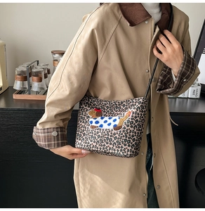 Detail of leopard print crossbody bag featuring cute dachshund embroidery and thin strap