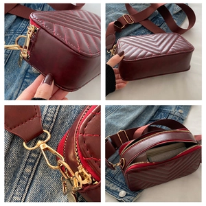 Detail view of burgundy quilted camera bag with golden hardware and adjustable wide strap