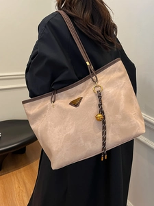 Grand sac cabas beige et marron avec logo triangle en métal porté par un mannequin