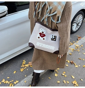 Detail of cream canvas bag with brown leather trim and 87 bear embroidery patch