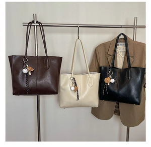 Detailed view of large vintage tote bags in dark brown, cream, and black on a rack