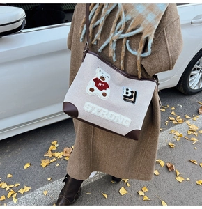 Detail of canvas tote with 3D bear design and leather trim in an autumn street setting