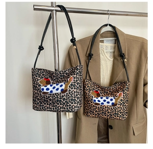 Détail d'un sac cabas léopard avec broderie de teckel et bandoulière à nœud noir