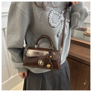 Detail view of the brown retro PU leather crossbody bag with woven knot charm and metal lock