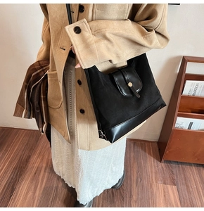 Détail du cabas en daim et cuir noir avec boucle dorée sur la bandoulière
