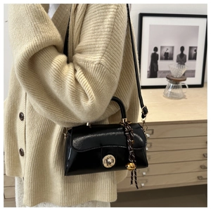 Detail of a vintage black crossbody bag with metal twist lock shown on a model