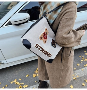 Detail of canvas tote bag with bear patch and leather trim in an autumn street setting