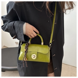 Close-up of grass green retro leather handbag with gold clasp and woven rope charm detail