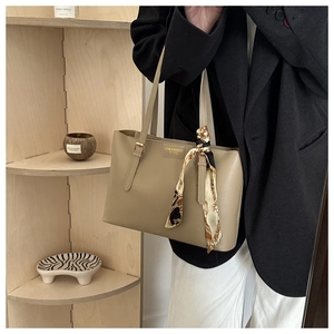 Détail du sac cabas en cuir kaki avec lettrage doré et foulard décoratif en soie