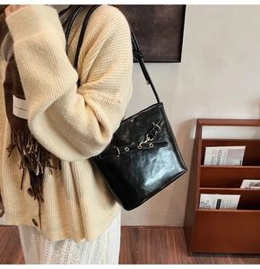 Detail of glossy black leather bucket bag with metallic buckle and retro vintage finish