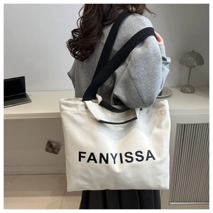 Détail d'un grand sac cabas en toile avec lettrage FANYISSA porté à l'épaule