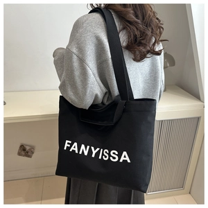 Gros plan sur le sac fourre-tout en toile noire avec lettrage FANYISSA et large bandoulière