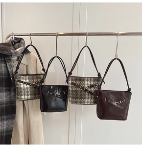 Detail of vintage tote bags in plaid fabric and glossy leather hanging on a rack