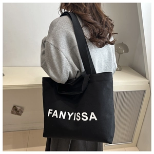 Détail d'un sac fourre-tout noir avec imprimé FANYISSA porté sur un sweat à capuche